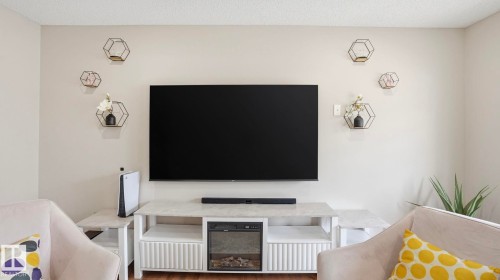 Media console with integrated electric fireplace, wall-mounted display, and decorative hexagonal shelving - 8210 180 Avenue Nw, Edmonton, AB - Indoor