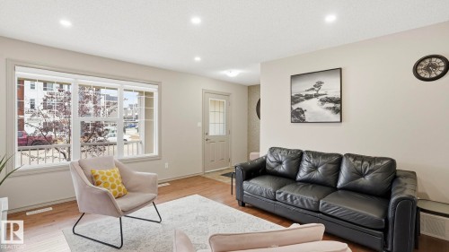 Bright living area featuring wood-finish flooring, recessed lighting, and a large multi-pane window - 8210 180 Avenue Nw, Edmonton, AB - Indoor Photo Showing Living Room
