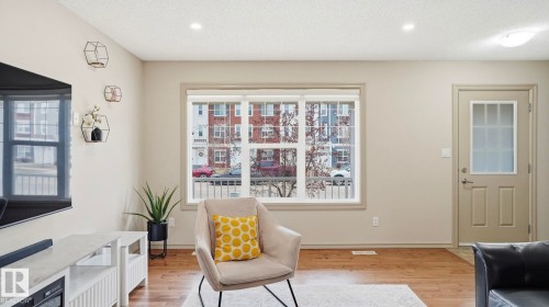 Living area featuring recessed lighting, wood-finish flooring, a prominent window with white trim, and a panel door with frosted glass inserts - 8210 180 Avenue Nw, Edmonton, AB - Indoor