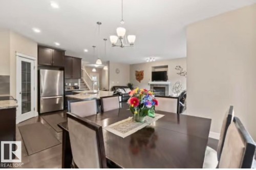 Dining area featuring a dark wood-finish table, upholstered chairs, and an overhead chandelier - 1944 67 Street, Edmonton, AB - Indoor Photo Showing Dining Room