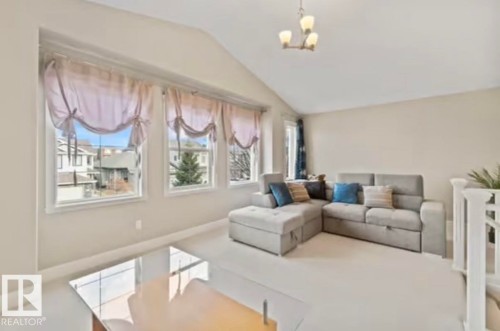 Vaulted ceiling living area featuring multiple windows, neutral wall tones, and carpet flooring - 1944 67 Street, Edmonton, AB - Indoor Photo Showing Living Room