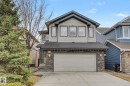 Two-story home featuring a stone facade, attached two-car garage, gray siding, and multiple front-facing windows - 1944 67 Street, Edmonton, AB  - Outdoor 