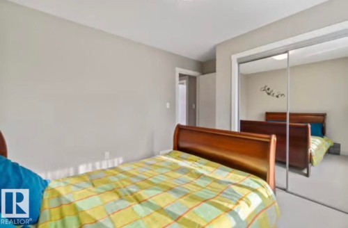 Bedroom featuring light gray wall paint, white trim, and mirrored sliding closet doors - 1944 67 Street, Edmonton, AB - Indoor Photo Showing Bedroom