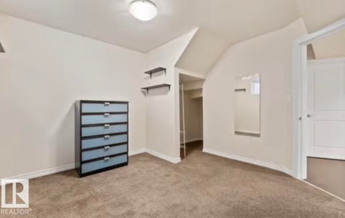 Carpeted room featuring a ceiling-mounted light fixture, white baseboards, and an architectural ceiling detail - 1944 67 Street, Edmonton, AB - Indoor