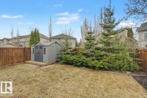 Backyard featuring a gray utility shed on a wood-finish platform, surrounded by a wood privacy fence - 1944 67 Street, Edmonton, AB - Outdoor