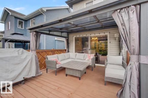 Expansive wood-finish deck with a clear-panel patio cover and privacy curtains - 1944 67 Street, Edmonton, AB - Outdoor With Deck Patio Veranda With Exterior