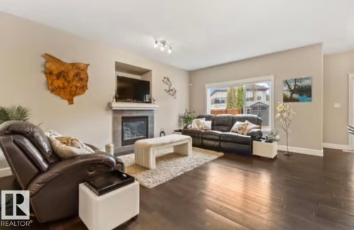 Living area featuring dark wood-finish flooring and neutral wall tones - 1944 67 Street, Edmonton, AB - Indoor Photo Showing Living Room With Fireplace