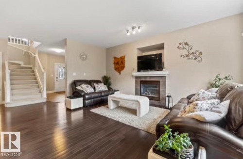 Living area featuring dark wood-finish flooring and a tiled fireplace with a white mantel - 1944 67 Street, Edmonton, AB - Indoor Photo Showing Living Room With Fireplace