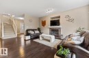 Living area featuring dark wood-finish flooring and a tiled fireplace with a white mantel - 1944 67 Street, Edmonton, AB  - Indoor Photo Showing Living Room With Fireplace 