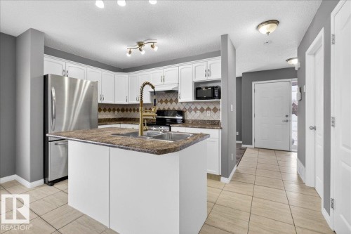 Kitchen with white cabinetry, stainless steel appliances, light tile patterned floors, a textured ceiling, and an island with sink - 150 Acacia Circle, Leduc, AB - Indoor Photo Showing Kitchen With Upgraded Kitchen