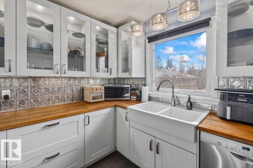 White cabinetry with glass door inserts, wood-finish countertops, and a decorative tile backsplash - 10756 133 Street, Edmonton, AB - Indoor Photo Showing Kitchen With Double Sink
