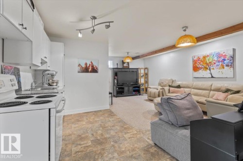 Kitchen area featuring white cabinetry, a white electric range, and stone-finish flooring - 10756 133 Street, Edmonton, AB - Indoor Photo Showing Kitchen