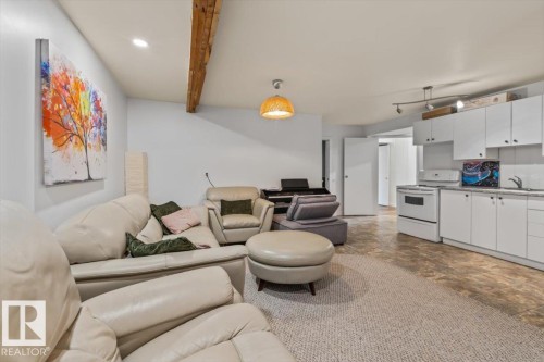Open-concept living space featuring a partial kitchen with white cabinetry and a built-in range - 10756 133 Street, Edmonton, AB - Indoor