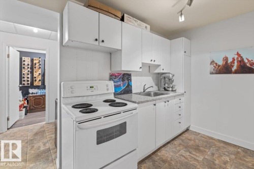 Kitchenette featuring white cabinetry, a white electric range, a stainless steel sink, and speckled countertops - 10756 133 Street, Edmonton, AB - Indoor Photo Showing Kitchen