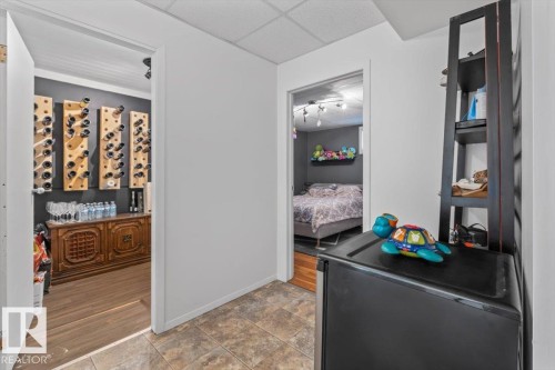 Dedicated storage area featuring multiple wall-mounted bottle racks, a built-in wooden console, and wood-finish flooring - 10756 133 Street, Edmonton, AB - Indoor Photo Showing Other Room