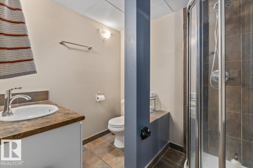 Bathroom featuring a white vanity with an undermount sink, a brown-toned countertop, and chrome fixtures - 10756 133 Street, Edmonton, AB - Indoor Photo Showing Bathroom