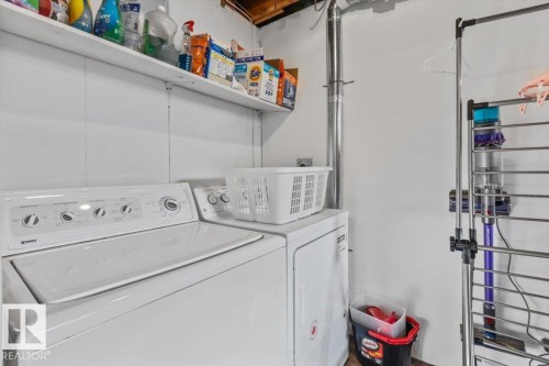 Laundry area featuring white appliances, a washer, a dryer, and built-in shelving - 10756 133 Street, Edmonton, AB - Indoor Photo Showing Laundry Room