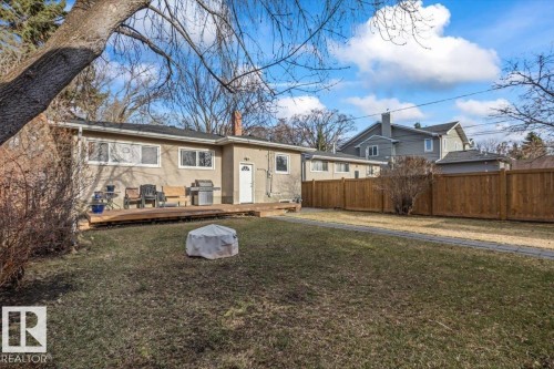Spacious backyard with a wooden fence, featuring a large wooden deck and a stucco exterior - 10756 133 Street, Edmonton, AB - Outdoor