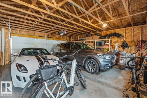Two-car garage featuring a concrete floor, exposed wood ceiling trusses, and raw wood-paneled walls - 10756 133 Street, Edmonton, AB - Indoor Photo Showing Garage
