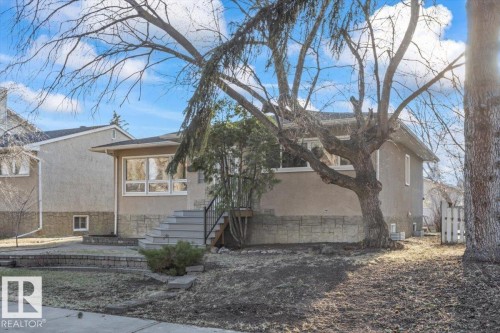 Stucco exterior with stone veneer accents, multiple large windows, and a tiered stone retaining wall - 10756 133 Street, Edmonton, AB - Outdoor
