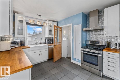 Kitchen featuring wood-finish countertops, a farmhouse sink, stainless steel appliances, and grey tiled flooring - 10756 133 Street, Edmonton, AB - Indoor Photo Showing Kitchen