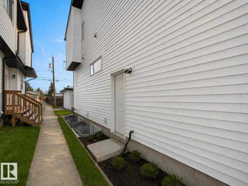 White horizontal siding exterior with a concrete entry pad and an exterior lighting fixture - 10913 159 Street, Edmonton, AB - Outdoor With Exterior