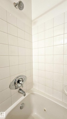 Shower-over-tub combination with white textured wall tiling - 415 15503 106 Street, Edmonton, AB - Indoor Photo Showing Bathroom
