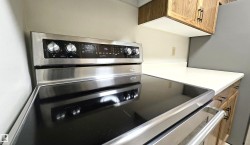 Stainless steel range featuring a sleek black cooktop, digital controls, and large knob hardware - 