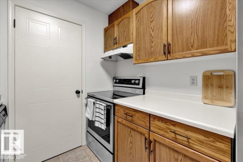 Kitchen featuring wood-finish cabinetry, white countertops, and stainless steel range - 415 15503 106 Street, Edmonton, AB - Indoor Photo Showing Kitchen