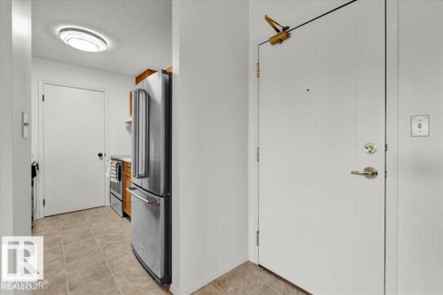 Entrance featuring a white panel door with brass hardware and an overhead door closer - 415 15503 106 Street, Edmonton, AB - Indoor Photo Showing Other Room