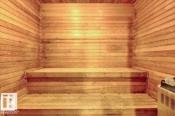 Built-in sauna featuring horizontal wood paneling, two-tiered wood benches, and an integrated sauna heater with stone accents - 