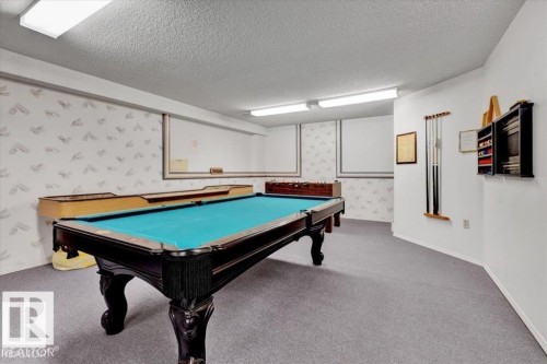 Recreation room featuring a pool table with a blue felt surface, light grey carpet flooring, and white walls - 415 15503 106 Street, Edmonton, AB - Indoor Photo Showing Other Room