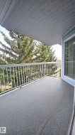 Private balcony featuring a textured gray surface, white metal railing, and an overhead perforated soffit - 