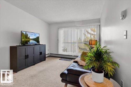 Living area featuring carpeting, white walls, and a large sliding glass door - 415 15503 106 Street, Edmonton, AB - Indoor