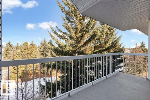 Spacious balcony featuring a gray concrete surface, light-colored metal railing, and a slatted ceiling overhead - 415 15503 106 Street, Edmonton, AB - Outdoor
