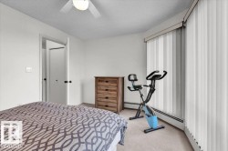 Bedroom featuring white walls, textured carpet flooring, and a ceiling fan with integrated lighting - 