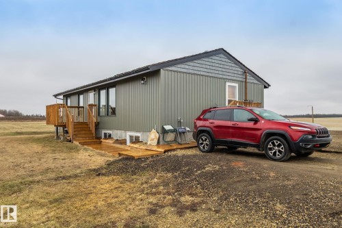 Single-story residence featuring vertical panel siding and shingle accents - 23127 Twp Rd 502, Rural Leduc County, AB - Outdoor
