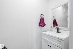 White vanity with an integrated sink, matte black faucet, and an ornate framed mirror - 