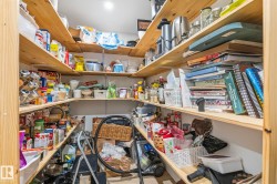 Walk-in pantry featuring extensive wood shelving, recessed lighting, and ample storage space - 