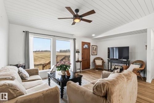 Living area featuring wood-finish flooring, a white planked vaulted ceiling, and a ceiling fan with integrated lighting - 23127 Twp Rd 502, Rural Leduc County, AB - Indoor Photo Showing Living Room
