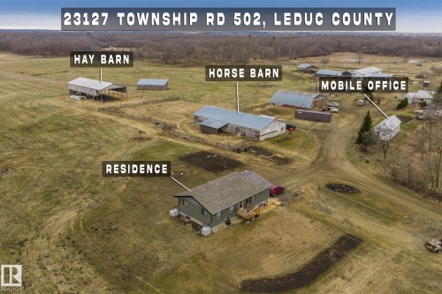Expansive property featuring a residence with a deck, a hay barn, a horse barn, and a separate mobile office structure, all set within a rural landscape - 23127 Twp Rd 502, Rural Leduc County, AB - Outdoor With View