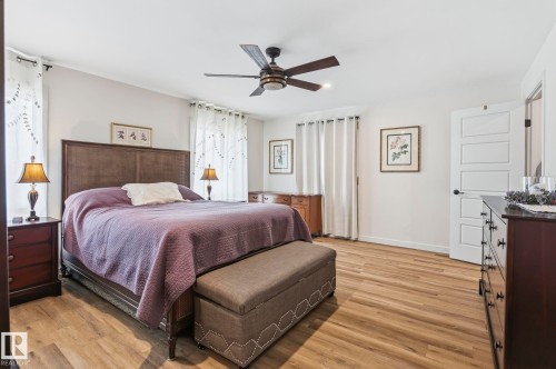 Spacious room featuring wood-finish flooring, a contemporary ceiling fan, white paneled door, and ample natural light from multiple windows - 23127 Twp Rd 502, Rural Leduc County, AB - Indoor Photo Showing Bedroom