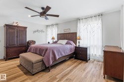 Spacious room featuring wood-finish flooring, light grey walls, and a ceiling fan with integrated lighting - 