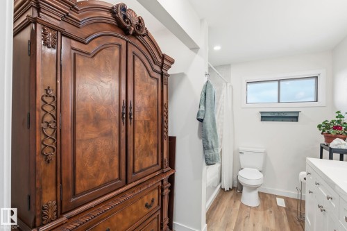 Bathroom featuring light wood-finish flooring, a white vanity with multiple drawers, a toilet, and a window providing natural light - 23127 Twp Rd 502, Rural Leduc County, AB - Indoor Photo Showing Bathroom