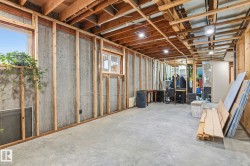 Expansive unfinished basement featuring concrete walls and flooring, wood framing, exposed wood ceiling joists, and multiple windows - 