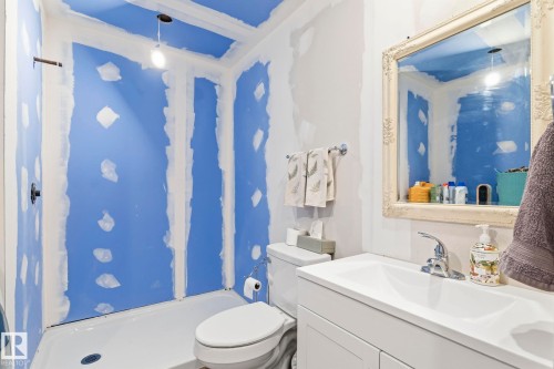 Bathroom featuring a white vanity with integrated sink, chrome faucet, white toilet, and a shower stall with a white base - 23127 Twp Rd 502, Rural Leduc County, AB - Indoor Photo Showing Bathroom