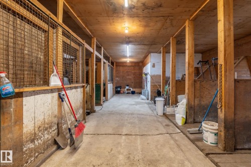 Interior barn walkway featuring multiple stalls with wood construction and metal mesh upper sections - 23127 Twp Rd 502, Rural Leduc County, AB - Indoor