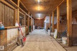 Interior barn walkway featuring multiple stalls with wood construction and metal mesh upper sections - 