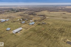 Expansive rural property featuring multiple outbuildings, open fields, and areas of mature trees - 