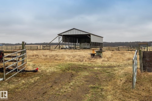 Open-sided barn structure with metal roofing, perimeter fencing, and a large open field - 23127 Twp Rd 502, Rural Leduc County, AB - Outdoor With View